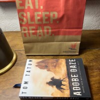 Adobe Daze Book Sitting On Wooden Table In Front of Indie Bound Paper Bag Adobe Daze Book Sitting On Wooden Table In Front of Indie Bound Paper Bag